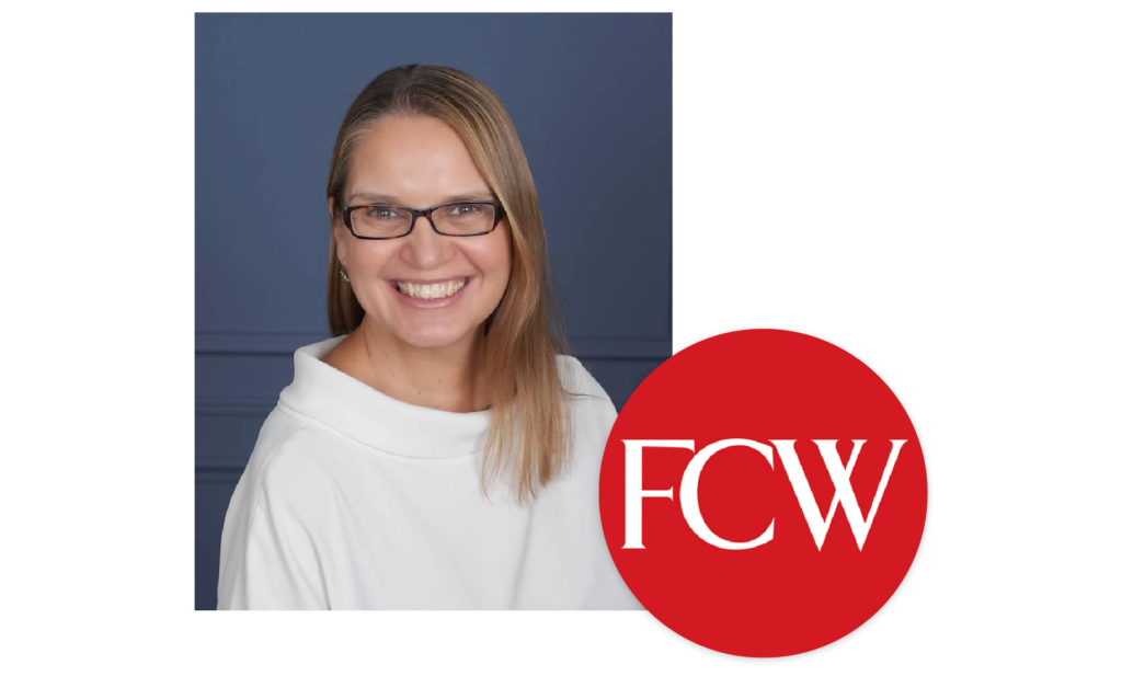 Nicole Carey smiling at camera wearing glasses and a white sweater with the initialism FCW in a red circle.
