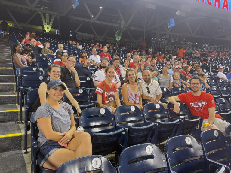 DIS employees smiling at the camera while sitting at a DC Nationals baseball game.